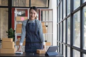 Portrait of Asian young woman SME working with a box at home the workplace.start-up small business owner, small business entrepreneur SME or freelance business online and delivery concept. photo