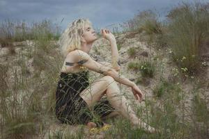 Dreaming woman in black dress sitting on sand hill scenic photography photo