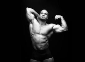 sports man standing on a black background, doing sports photo