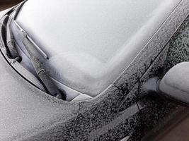 Ventana de coche cubierta de nieve con limpiaparabrisas, macro, primer plano foto