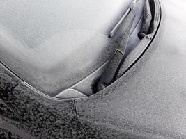 Ventana de coche cubierta de nieve con limpiaparabrisas, macro, primer plano foto