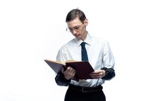 un hombre de negocios con corbata y gafas con una revista en las manos sobre un fondo blanco y aislado foto