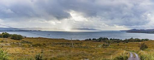 Panorama picture of typical Irish coast line with green meadows and blue waters during daytime photo