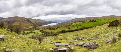 Panorama picture of typical Irish landscape with green meadows and rough mountains during daytime photo