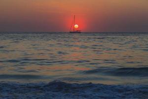 puesta de sol sobre el mar con velero