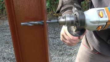 Man hands drilling metal fence to metal construction. Building a metal fence with a drill and screw. Close up of his hand and the tool in a diy concept. video