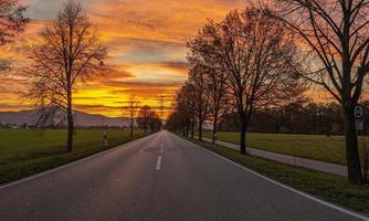 Image of a colorful and high-contrast sunrise with bright cloud formations along an avenue photo