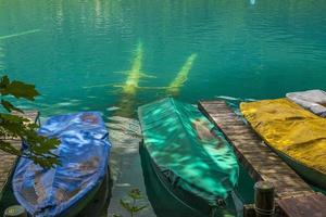 Boat pier with paddle boats and sunk trunks at east shore of Weisensee lake in Austria photo
