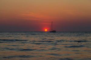 Sunset over the sea with boat silhouette photo