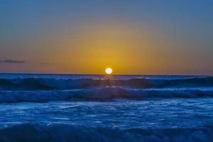 Sunset over ocean with breaking waves photo