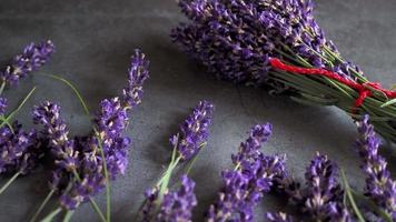 A bouquet of lavender with a red ribbon lies on a gray surface video