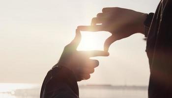 concepto de planificación y visión del comienzo del año nuevo, manos de mujer haciendo gestos de marco para encontrar el foco al atardecer, mujer buscando perspectiva para capturar el significado de un próximo objetivo claro. foto