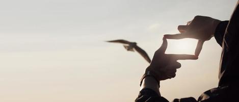 Planning and vision concept of new year's start, woman hands making frame gesture find focus at sunset, woman looking for perspective to capture the meaning of a clear upcoming target. photo