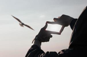 concepto de planificación y visión del comienzo del año nuevo, manos de mujer haciendo gestos de marco para encontrar el foco al atardecer, mujer buscando perspectiva para capturar el significado de un próximo objetivo claro. foto