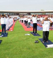 New Delhi, India, June 21 2022 - Group Yoga exercise session for people at Yamuna Sports Complex in Delhi on International Yoga Day, Big group of adults attending yoga class in cricket stadium photo