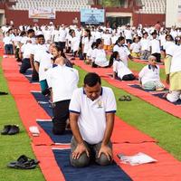 New Delhi, India, June 21 2022 - Group Yoga exercise session for people at Yamuna Sports Complex in Delhi on International Yoga Day, Big group of adults attending yoga class in cricket stadium photo