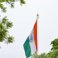 India flag flying high at Connaught Place with pride in blue sky, India flag fluttering, Indian Flag on Independence Day and Republic Day of India, tilt up shot, Waving Indian flag, Har Ghar Tiranga photo