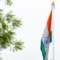 India flag flying high at Connaught Place with pride in blue sky, India flag fluttering, Indian Flag on Independence Day and Republic Day of India, tilt up shot, Waving Indian flag, Har Ghar Tiranga photo