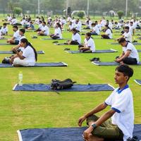 nueva delhi, india, 21 de junio de 2022 - sesión grupal de ejercicios de yoga para personas en el complejo deportivo yamuna en delhi el día internacional del yoga, gran grupo de adultos que asisten a clases de yoga en el estadio de cricket foto