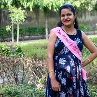 Indian couple posing for maternity baby shoot. The couple is posing in a lawn with green grass and the woman is falunting her baby bump in Lodhi Garden in New Delhi, India photo