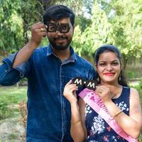 Indian couple posing for maternity baby shoot. The couple is posing in a lawn with green grass and the woman is falunting her baby bump in Lodhi Garden in New Delhi, India photo