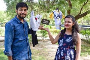 Indian couple posing for maternity baby shoot. The couple is posing in a lawn with green grass and the woman is falunting her baby bump in Lodhi Garden in New Delhi, India photo