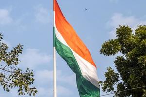 India flag flying high at Connaught Place with pride in blue sky, India flag fluttering, Indian Flag on Independence Day and Republic Day of India, tilt up shot, Waving Indian flag, Har Ghar Tiranga photo