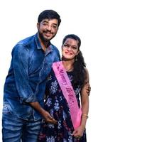 Indian couple posing for maternity baby shoot with white plain background. The couple is posing in a lawn with green grass and the woman is falunting her baby bump in Lodhi Garden in New Delhi, India photo