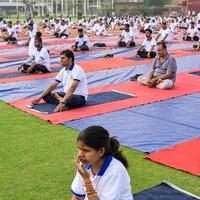 New Delhi, India, June 21 2022 - Group Yoga exercise session for people at Yamuna Sports Complex in Delhi on International Yoga Day, Big group of adults attending yoga class in cricket stadium photo