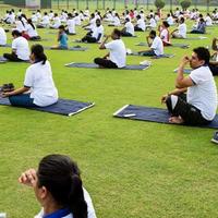 New Delhi, India, June 21 2022 - Group Yoga exercise session for people at Yamuna Sports Complex in Delhi on International Yoga Day, Big group of adults attending yoga class in cricket stadium photo