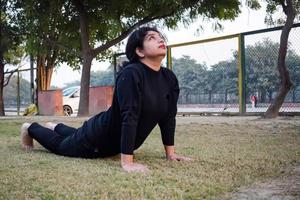 Young Indian woman practicing yoga outdoor in a park. Beautiful girl practice basic yoga pose. Calmness and relax, female happiness. Basic Yoga poses outdoor photo