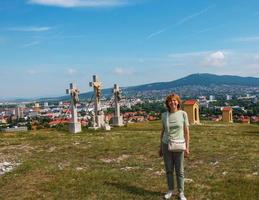 A mature middle-aged woman with blond hair stands in front of an observation deck on Mount Calvaria in the city of Nitra in Slovakia. photo