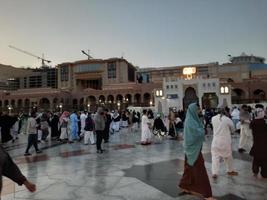 medina, arabia saudita, diciembre de 2022 - hermosa vista nocturna en masjid al-nabawi, los visitantes son vistos en las luces de la mezquita en las instalaciones de la mezquita. foto