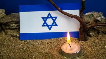 bandera israelí y velas encendidas frente a ella, día de la memoria del holocausto foto
