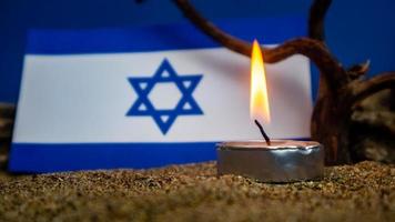 bandera israelí y velas encendidas frente a ella, día de la memoria del holocausto foto