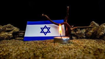 Israeli flag and candles burning in front of it, Holocaust memory day