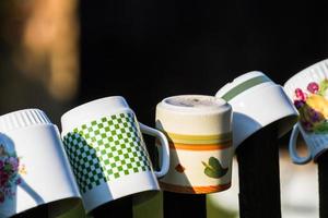 a row of coffee mugs stacked on the fence photo