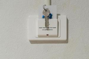 tarjeta inteligente con llave insertada en un enchufe blanco con lectura de texto insertar tarjeta inteligente para energía instalada en una pared blanca en una lujosa habitación de hotel o resort foto