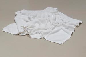 Used white towel untidily lying on brown floor in hotel or resort room after guest's use in toilet or restroom when taking a shower photo