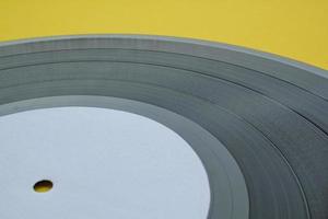 Close up of black old vinyl record play disc vintage on a yellow background with copy space for text. Retro LP history, nostalgia concept. Sound technology for DJ to mix music. Flat lay, top view photo