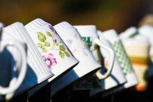 a row of coffee mugs stacked on the fence photo