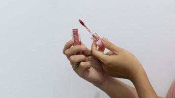 Beauty and makeup. Young lady holding tube of lipstick over white background, closeup photo