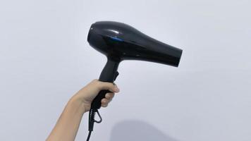 Black plastick hair dryer with black buttons in hand. Isolated on white background. Home appliance, heat air blower for salon. photo