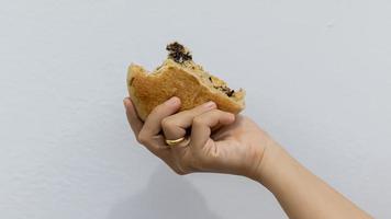 mano de mujer sosteniendo un donut de chocolate contra un fondo blanco foto