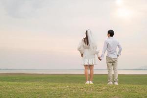 Happy young Asian couple in bride and groom clothing photo