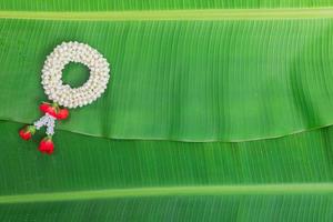 Songkran Festival background with jasmine garland on green banana leaf background photo