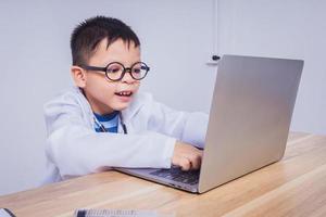 niño asiático doctor usando una computadora portátil foto