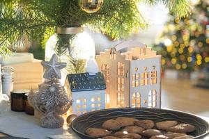 Festive Christmas decor in table, homemade cakes for breakfast, bakery cookies. Cozy home, christmas tree with fairy lights garlands. New Year, christmas mood photo