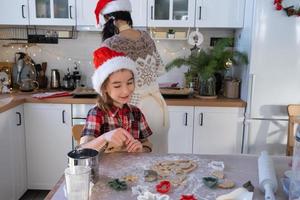 Mom and daughter in the white kitchen are preparing cookies for Christmas and new year. Family day, preparation for the holiday, learn to cook delicious pastries, cut shapes out of dough with molds photo