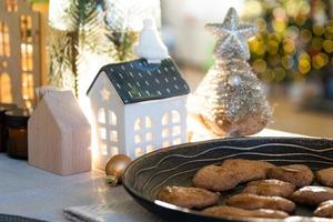 decoración navideña festiva en la mesa, pasteles caseros para el desayuno, galletas de panadería. hogar acogedor, árbol de navidad con guirnaldas de luces de hadas. año nuevo, estado de ánimo navideño